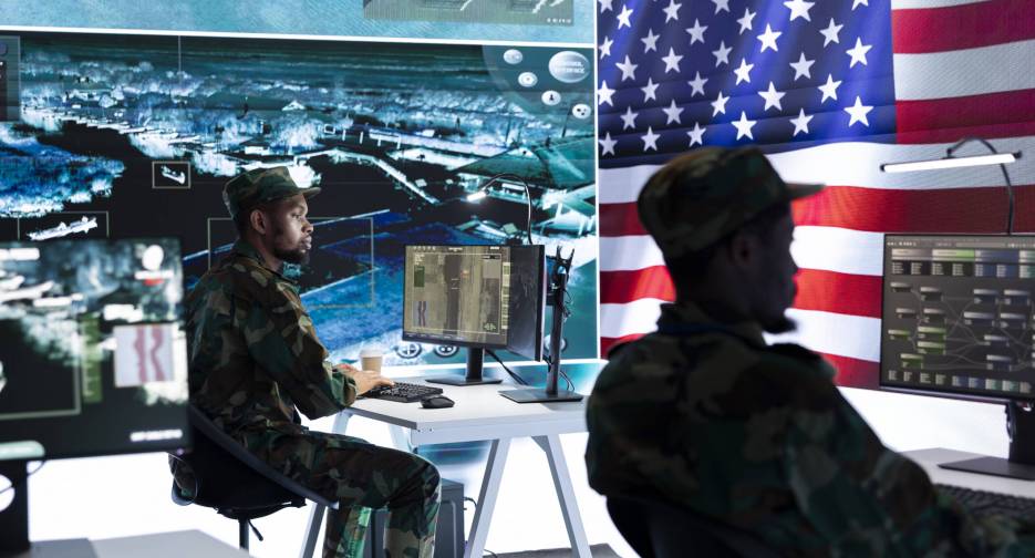 US military officer supervising threat detection activity in high tech office, examining top secret data on big screen. American army soldiers managing hybrid war, cyber attack prevention.